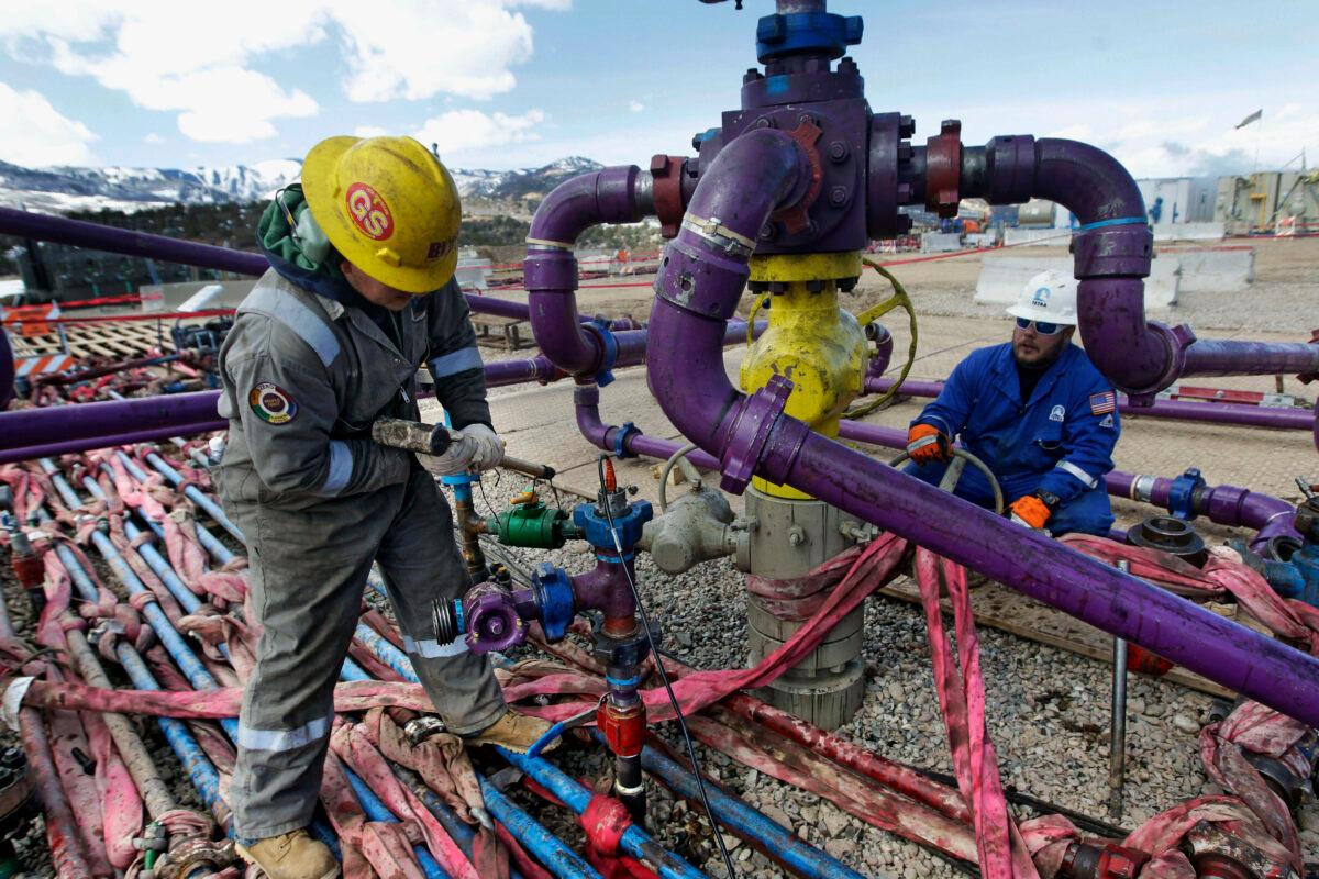 Workers tend to a well head during a hydraulic fracturing operation outside Rifle, Colo., on March 29, 2013. ( Brennan Linsley/AP Photo )